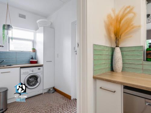 a laundry room with a washing machine and a vase on a counter at Renovated 3BR One Street to Beach in Victor Harbor