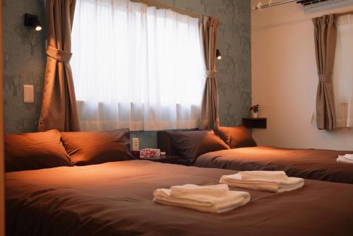 大阪市にあるnestay terrace house osaka tsutenkakuのベッドルーム1室(ベッド2台、タオル付)