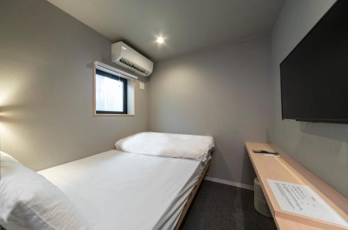 Habitación pequeña con 2 camas y TV. en Boxi Hakata 1, en Fukuoka