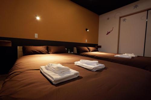 大阪市にあるnestay terrace house osaka tsutenkakuのベッドの上に座る白いタオル2枚