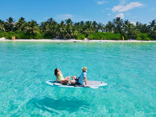 two girls sitting on a paddle board in the ocean at Ramzu Villa Thoddoo in Thoddoo