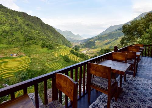 d'un balcon avec des tables et des chaises donnant sur la vallée. dans l'établissement Maison de Lao Chai, à Sa Pa