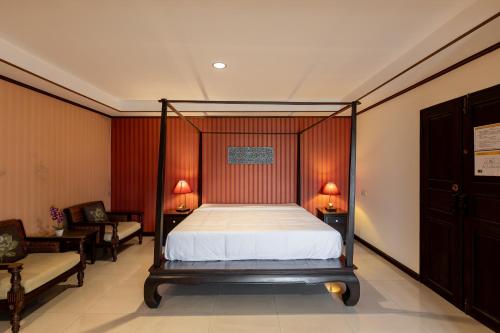 a bedroom with a canopy bed and two chairs at Na Thapae Chiangmai Hotel in Chiang Mai