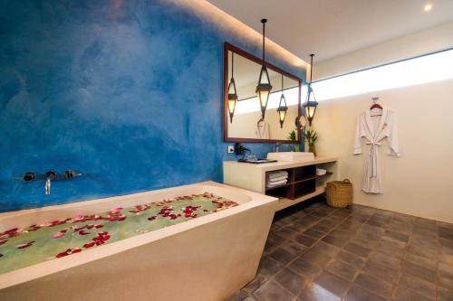 a bathroom with a bath tub with flowers on the floor at The Villa by Metta in Siem Reap