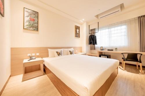 una camera d'albergo con un grande letto e una scrivania di TH Hotel a Città di Pingtung