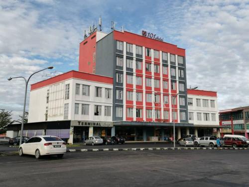 un edificio rojo y blanco con coches estacionados en un estacionamiento en 101 Hotel Bintulu, en Bintulu