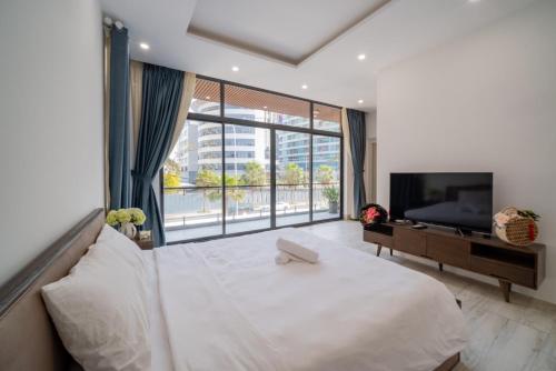 ein Schlafzimmer mit einem weißen Bett und einem großen Fenster in der Unterkunft Blue Sea Villa Vũng Tàu 5 in Vũng Tàu
