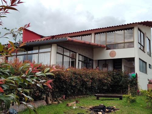 a house with a bench in front of it at Hospedaje Las Golondrinas - Tibirita, Cundinamarca in Tibirita