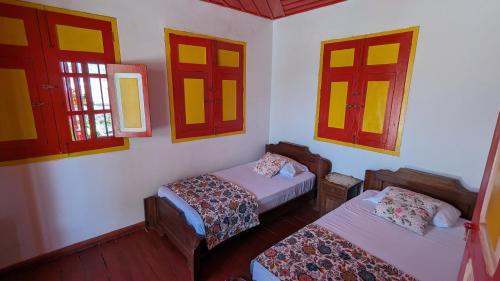 a room with two beds and two windows at Coronel's Peak Coffee House in Salento