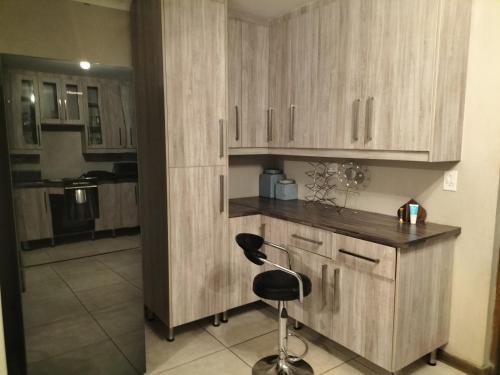 a kitchen with wooden cabinets and a chair in a room at AKANI Guesthouse Cosmo city in Roodepoort
