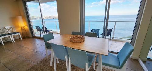 a table and chairs in a room with a view of the ocean at Breathtaking Ocean Views in Sydney