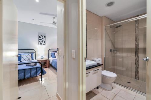 a bathroom with a toilet and a shower and a bed at Central City Apartment, Pool & Gym, 2 car parks in Darwin