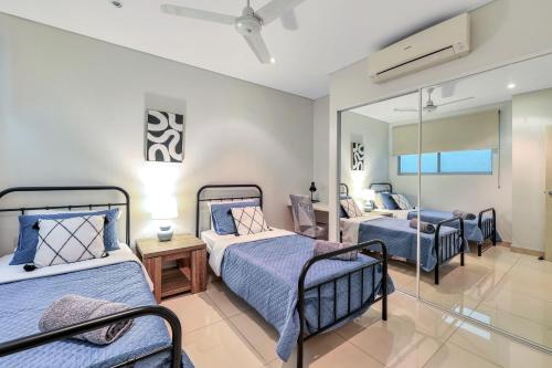 een slaapkamer met 4 bedden en een spiegel bij Central City Apartment, Pool & Gym, 2 car parks in Darwin