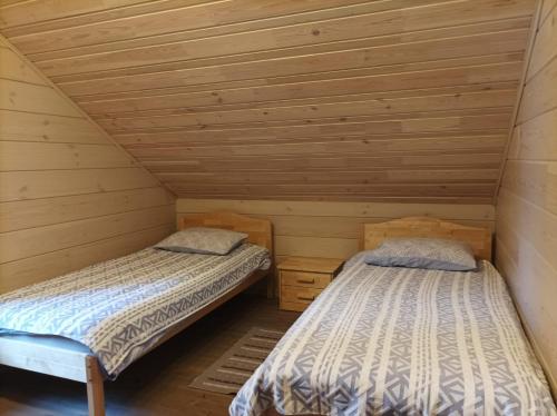 2 Betten in einem Zimmer mit Holzwänden in der Unterkunft Pirts Jaunakmeni in Priežmale