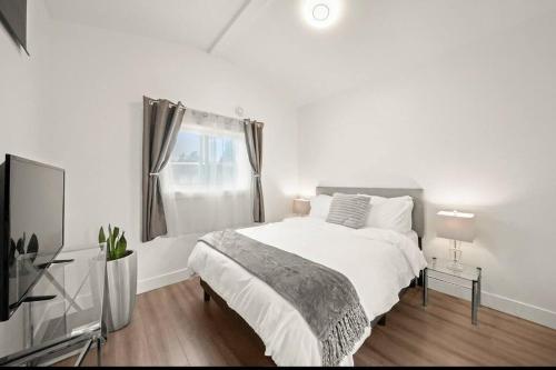 a white bedroom with a bed and a television at Entire NEW Cozy and Modern 2-storey HOUSE in Vancouver