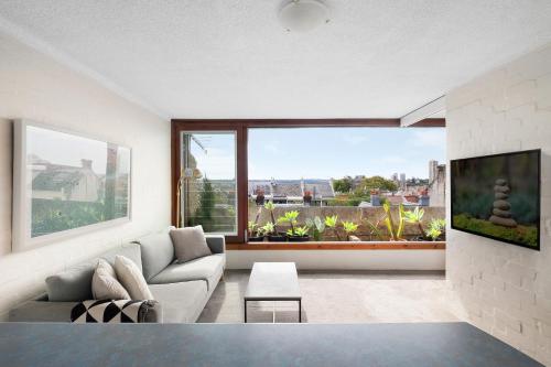 - un salon avec un canapé et une grande fenêtre dans l'établissement Boutique Paddington Apartment with CBD Views, à Sydney