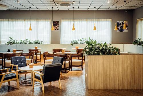 a restaurant with tables and chairs and plants at TH Hotel in Pingtung City