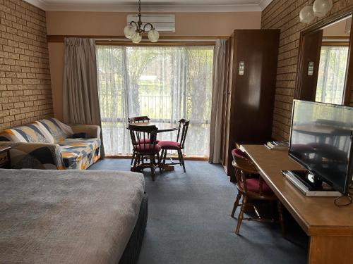 Una habitación de hotel con una cama y una mesa con televisión. en Barrass's John Bright Motor Inn, en Bright