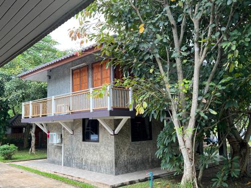 una casa con un balcón en el lateral. en Pup Resort River View (ปั๊บ รีสอร์ท), en Mae Taeng