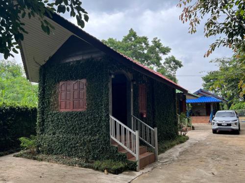 a building covered in ivy with a door and a porch at Pup Resort River View (ปั๊บ รีสอร์ท) in Mae Taeng