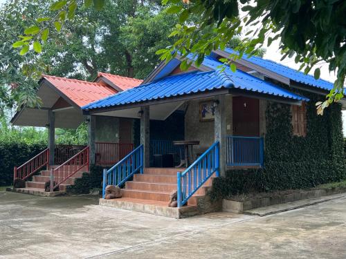 una pequeña casa con techo azul y escaleras en Pup Resort River View (ปั๊บ รีสอร์ท), en Mae Taeng