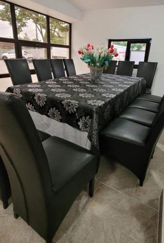 a dining room table with black chairs and a vase of flowers at Casa Domnească in Giurgiu