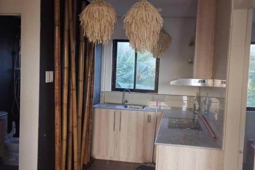 eine Küche mit einem Waschbecken, einem Fenster und Kronleuchtern in der Unterkunft Sunset Ocean View @ Breeze Life. in Panglao