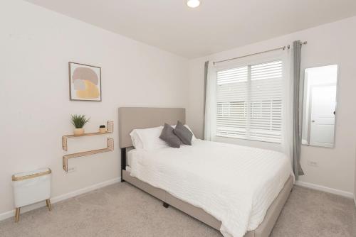 een witte slaapkamer met een bed en een raam bij Urban Oasis in Chicago’s Best Suburb in Naperville