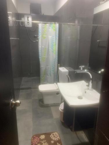 y baño con aseo, lavamanos y cortina de ducha. en Miracle Trail Kandy en Kandy