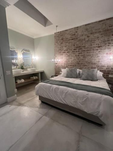 Cape Town的住宿－Two on Milner - ARUM COTTAGE - Stylish open-plan Guesthouse in Rondebosch，一间卧室设有一张大床和砖墙