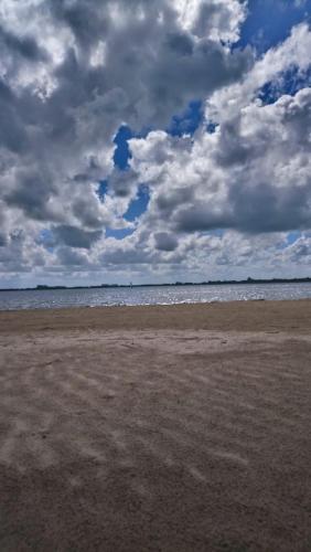 a sandy beach with a cloudy sky and the ocean at Meerhuuske Käthe in Südbrookmerland