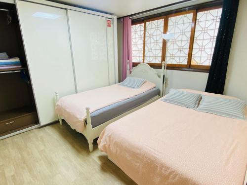 two beds in a room with two windows at Aroha house for Foreign guests only in Seoul