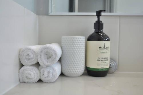 a bathroom shelf with towels and a bottle of wine at Balneaire 13 in Albany