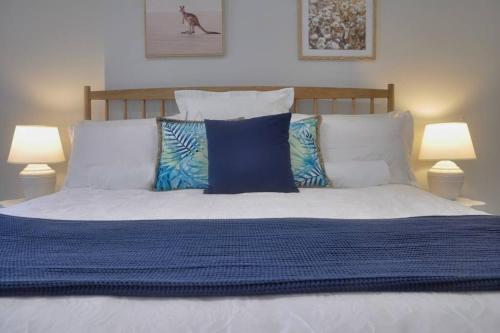 a bed with blue and white pillows and two lamps at Balneaire 13 in Albany