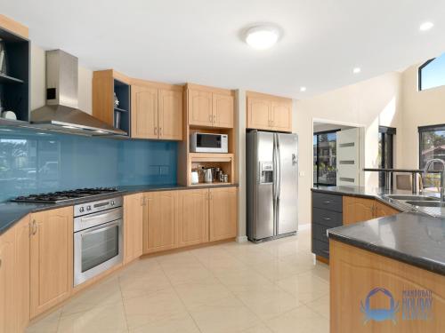 a large kitchen with wooden cabinets and stainless steel appliances at Canal Escape in Wannanup in Wannanup
