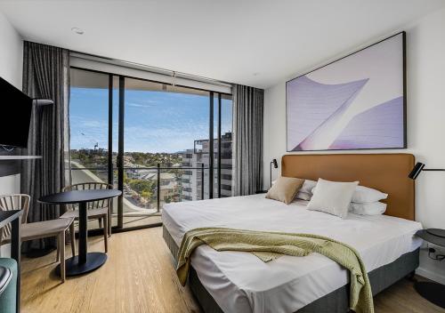 a bedroom with a large bed and a balcony at Rambla at South City SQ in Brisbane