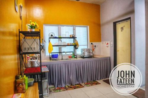 uma cozinha com paredes amarelas e um balcão em lumut manjung homestay john faten em Lumut
