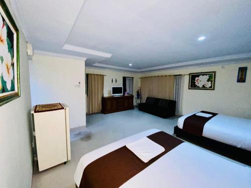 a hotel room with two beds and a couch at Dedy Beach Inn in Kuta