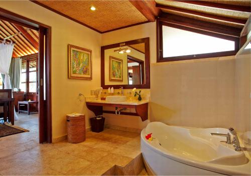a bathroom with a tub and a sink and a mirror at Bagus Jati Health & Wellbeing Retreat in Tegalalang