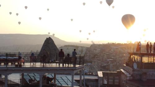 a group of hot air balloons flying over a city at Salkım Cave House in Göreme