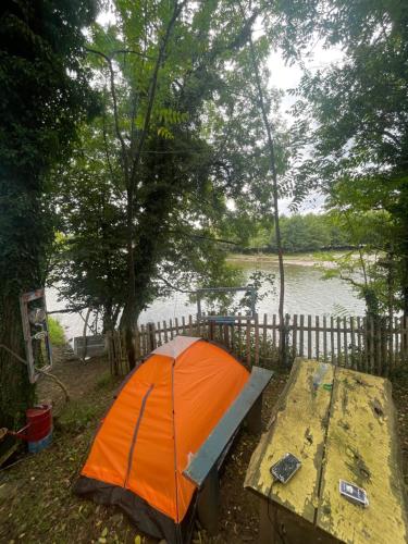 an orange umbrella sitting on a table next to a lake at Odo’s Guest House in Martvili