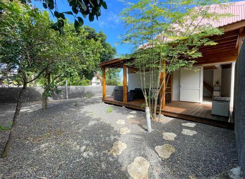a home with a porch with trees in the yard at La Chrysalide du Bassin - DODOTERLA in Saint-Joseph