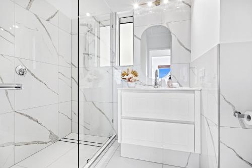 a white bathroom with a shower and a sink at The View in Cannonvale
