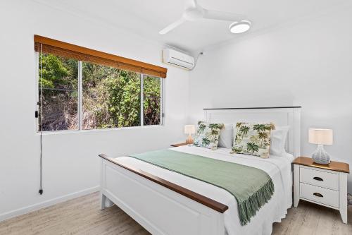 a white bedroom with a bed and a window at The View in Cannonvale