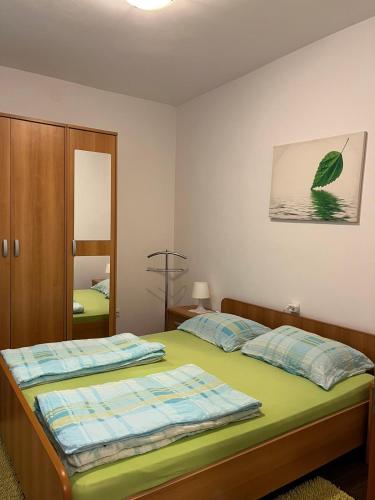 a bedroom with a bed with green sheets and a mirror at Gita in Omišalj