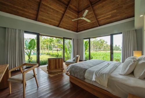 a bedroom with a large bed with a ceiling fan at Villa Lumia Bali in Ubud