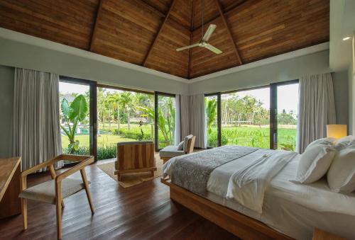 een slaapkamer met een groot bed en een plafondventilator bij Villa Lumia Bali in Ubud