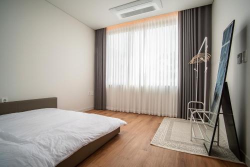 un dormitorio con una cama y una ventana grande en Ililsagye, en Seogwipo