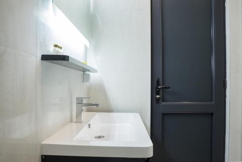 een badkamer met een witte wastafel en een zwarte deur bij Casino Motel Senator in Gevgelija