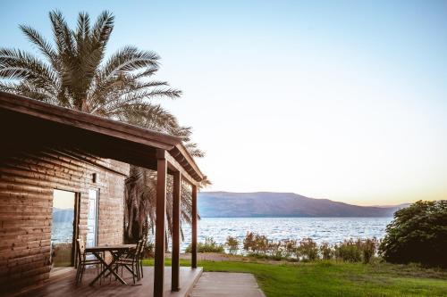 a house with a table and chairs on a porch next to the water at Daria- Authentic Israeli Experience in Samra